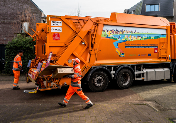 Een afvalophaler bij een vuilniswagen